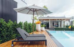 There are two lounge chairs and an umbrella in the courtyard corridor with a swimming pool